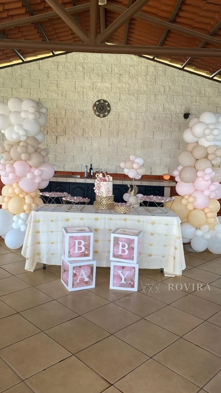 Baby shower con letras BABY, arco de globos en rosa y crema, y mesa de postres en salón rústico