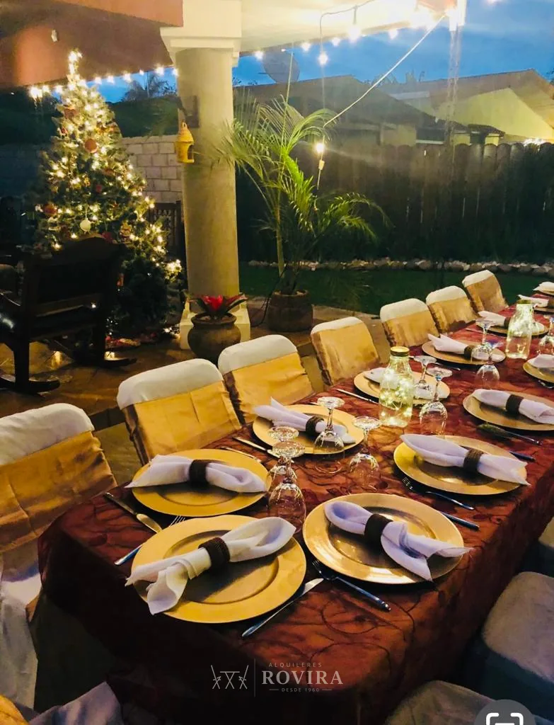 Mesa navideña elegante con mantel oscuro, platos base dorados y velas