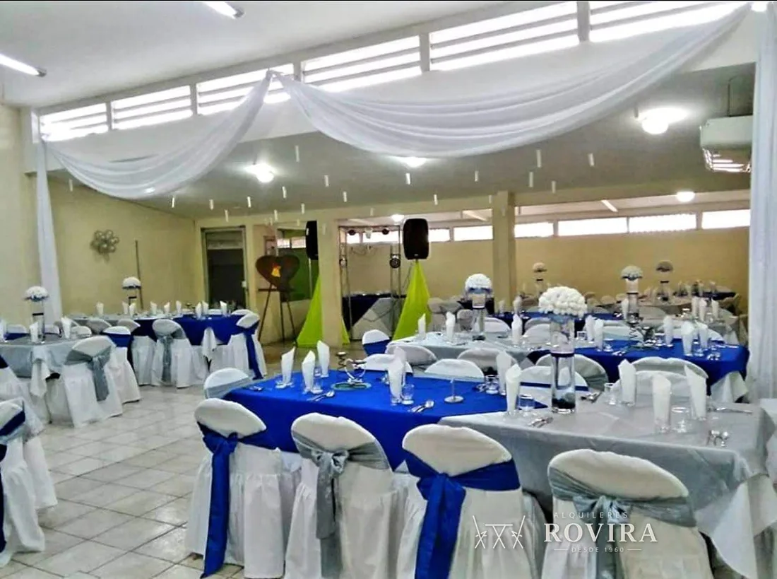 Techo de tela azul y blanco en salón techado, con sillas de lazo azul rey y plateado