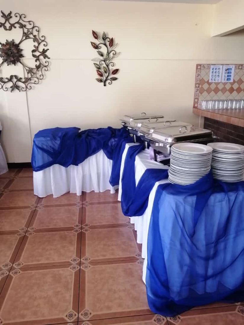 Techo de tela azul rey y verde lima en rancho al aire libre, mesas azul y lima