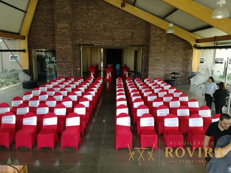 Montaje amplio con forros de silla rojos y blancos alineados en salón de eventos
