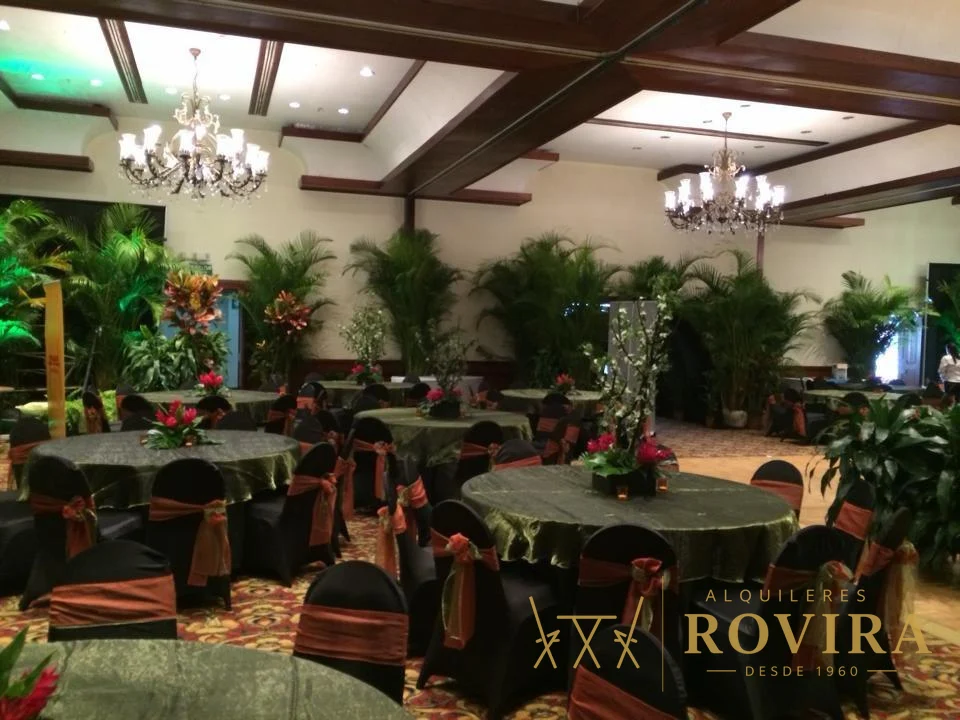 Salón con manteles verdes y negros y lazos dorados, ambiente elegante