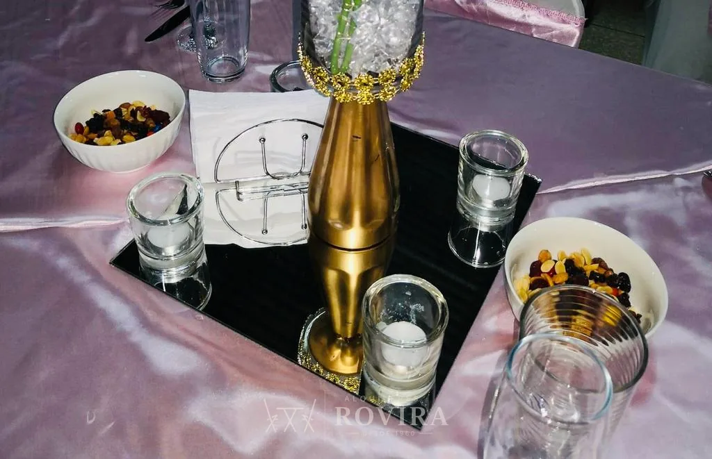 Centro de mesa dorado con vasos de vidrio, montaje de mesa de evento