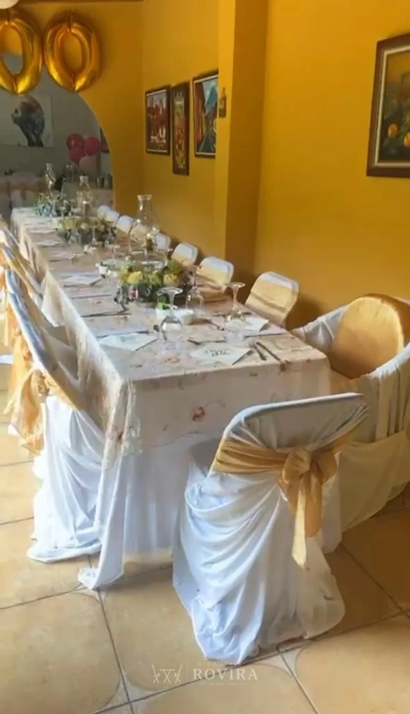 Mesa larga vestida de blanco en salón, montaje de evento