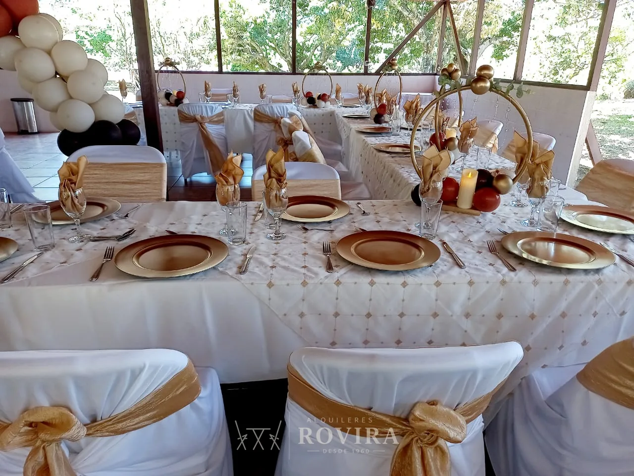 Montaje de mesa con lazos dorados en salón, servicio de vajilla y cristalería