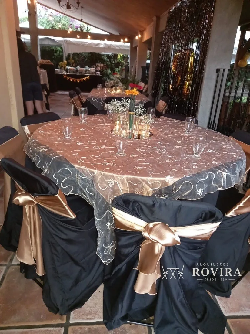 Mesa redonda vestida en dorado y negro con overlay de organza bordada, sillas negras con lazo dorado