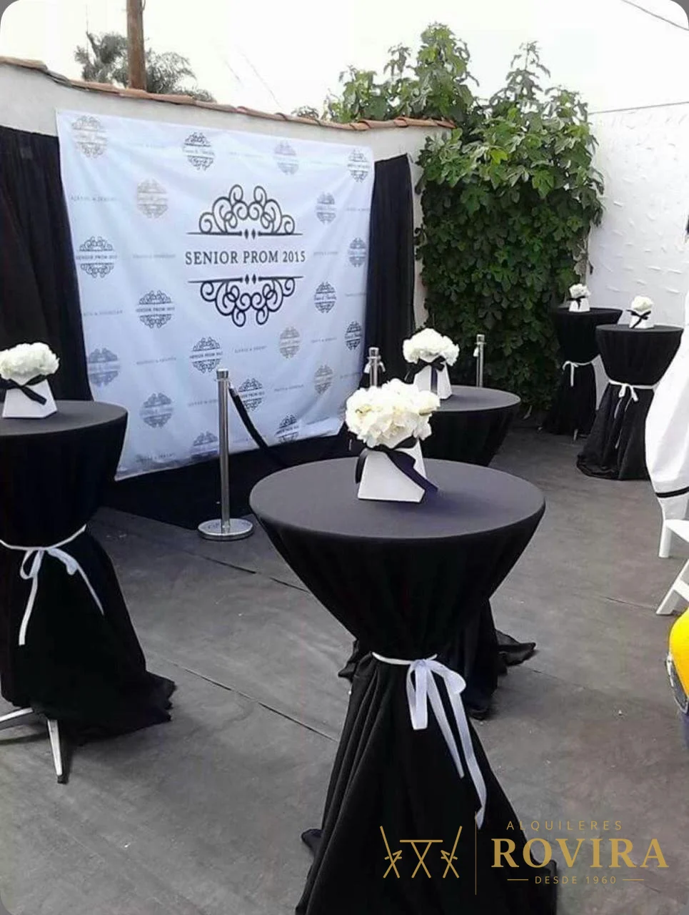 Mesas cocktaileras negras con centros de flores blancas, montaje de evento