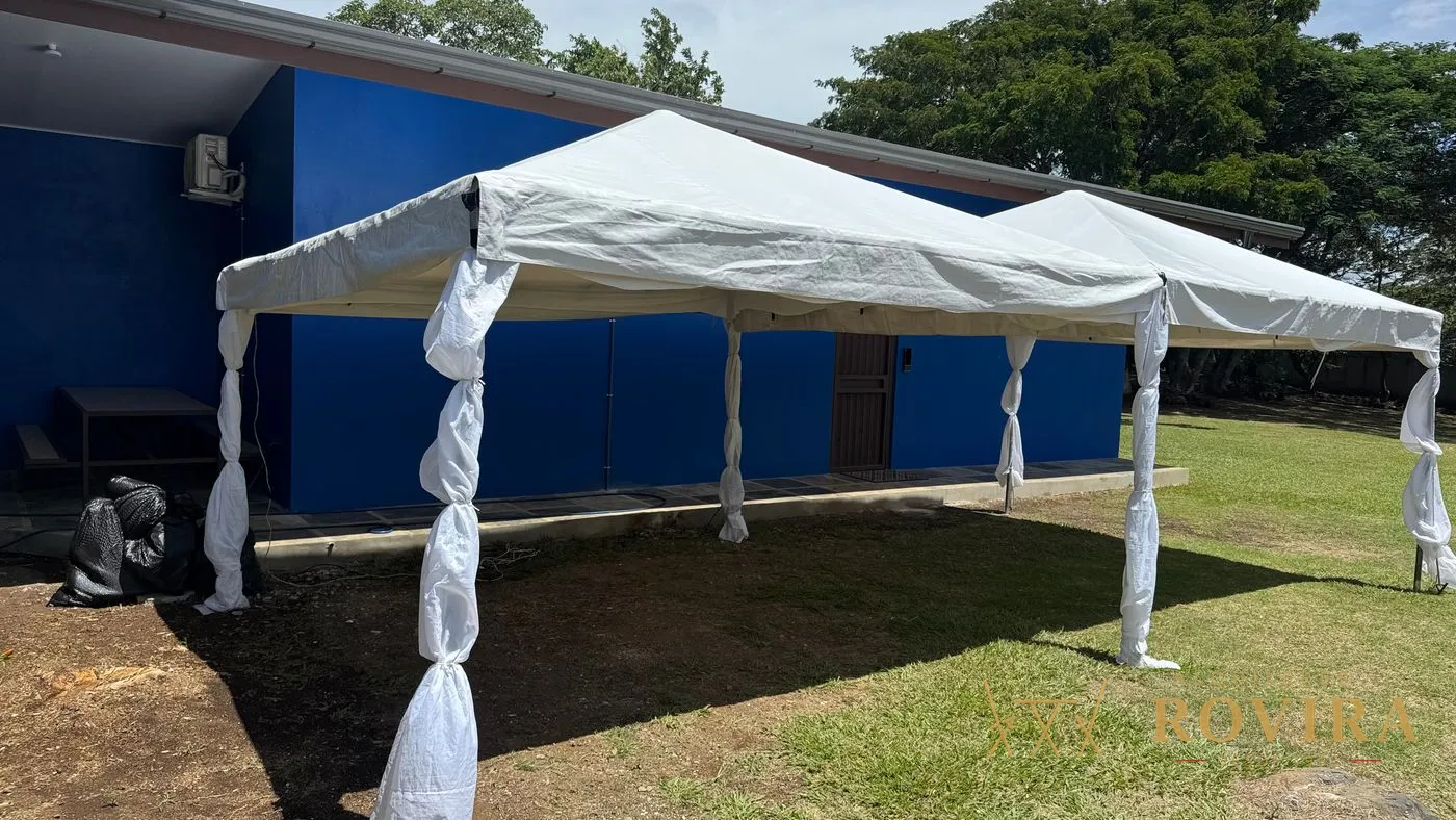 Toldo blanco modular armado en el jardín de una casa, estructura amplia sobre el césped