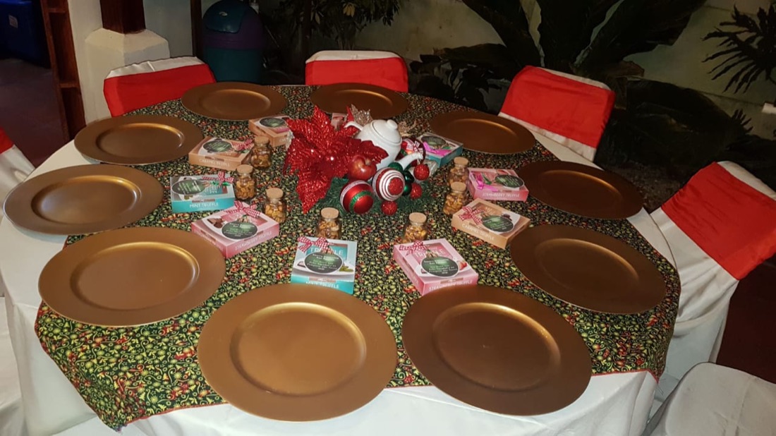 Mesa navideña con platos base dorados, flor de pascua roja y esferas navideñas de centro
