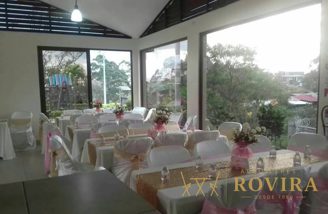 Baby shower de niña con forros de silla blancos y lazos rosados, salón con vista