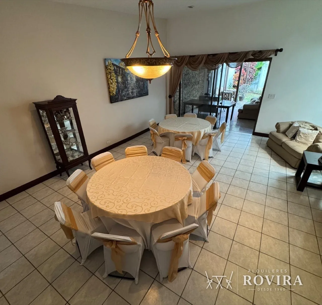 Mesas redondas vestidas en dorado con sillas con lazo dorado, en comedor y sala de casa