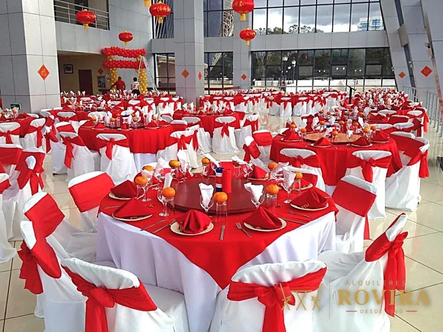 Salón con mesas en rojo y blanco, lazos rojos y faroles colgantes