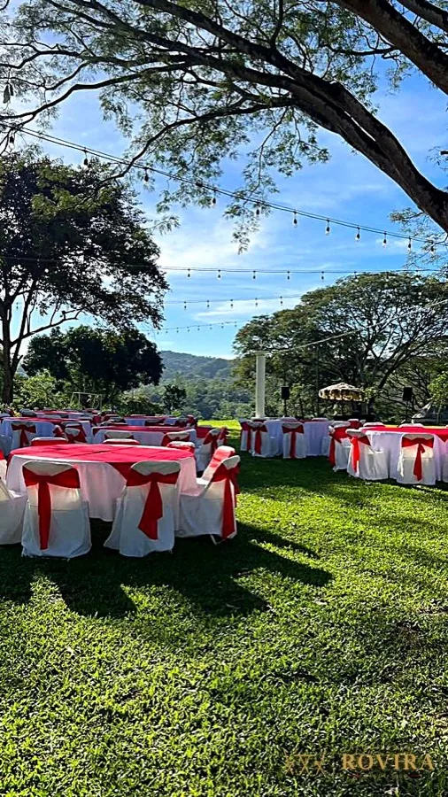 Jardín con mesas vestidas y luces guirnalda, vista a la montaña