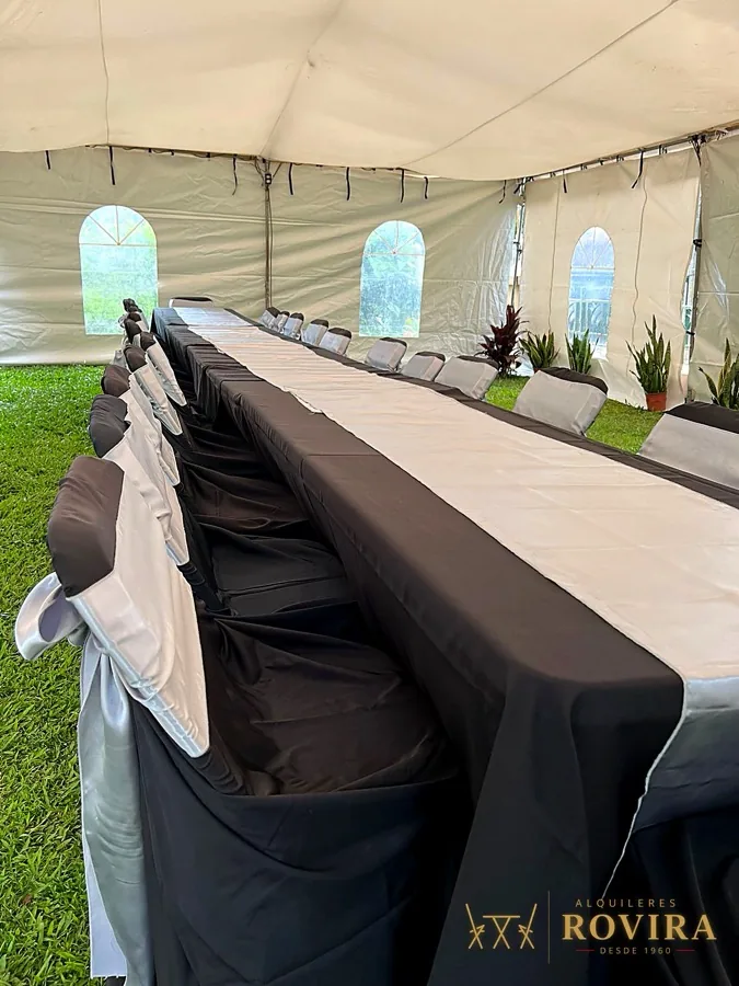 Mesa imperial larga bajo toldo con mantel negro y camino plateado, ventanas arqueadas del toldo