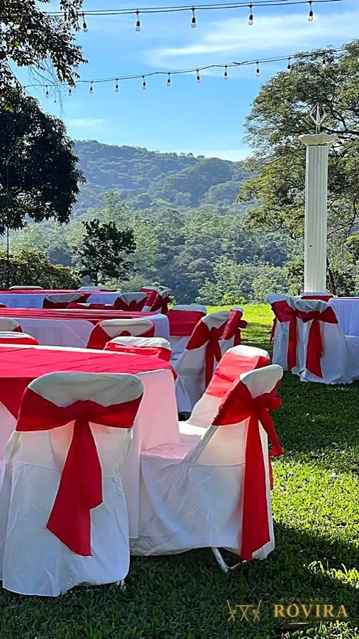 Mesas al aire libre con lazos rojos y luces, vista a la montaña