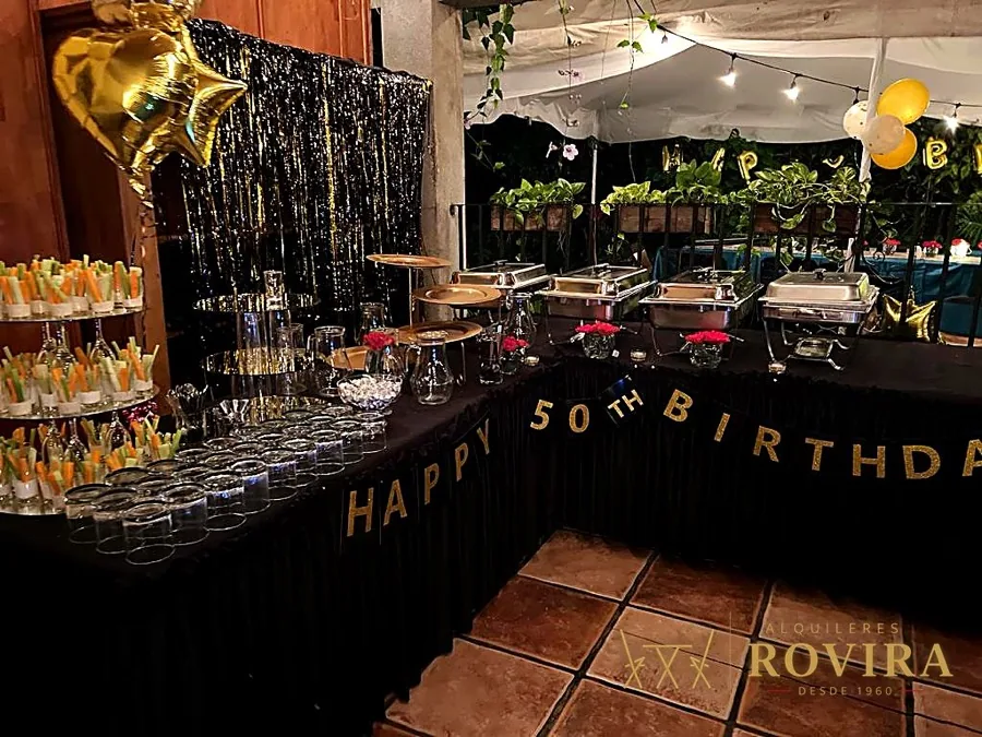 Buffet temático de cumpleaños 50 en dorado y negro, cortina metálica, globos dorados