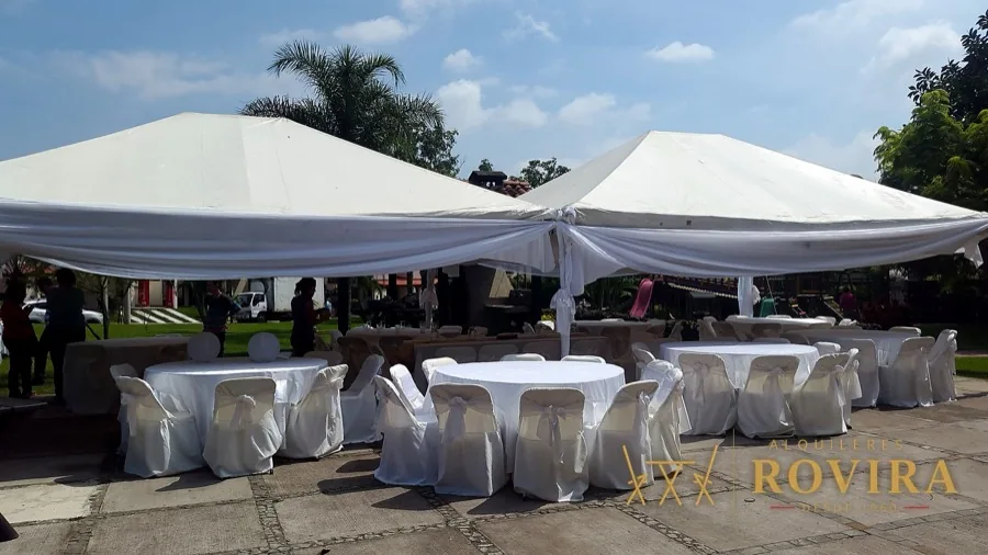 Dos toldos blancos con mesas en jardín