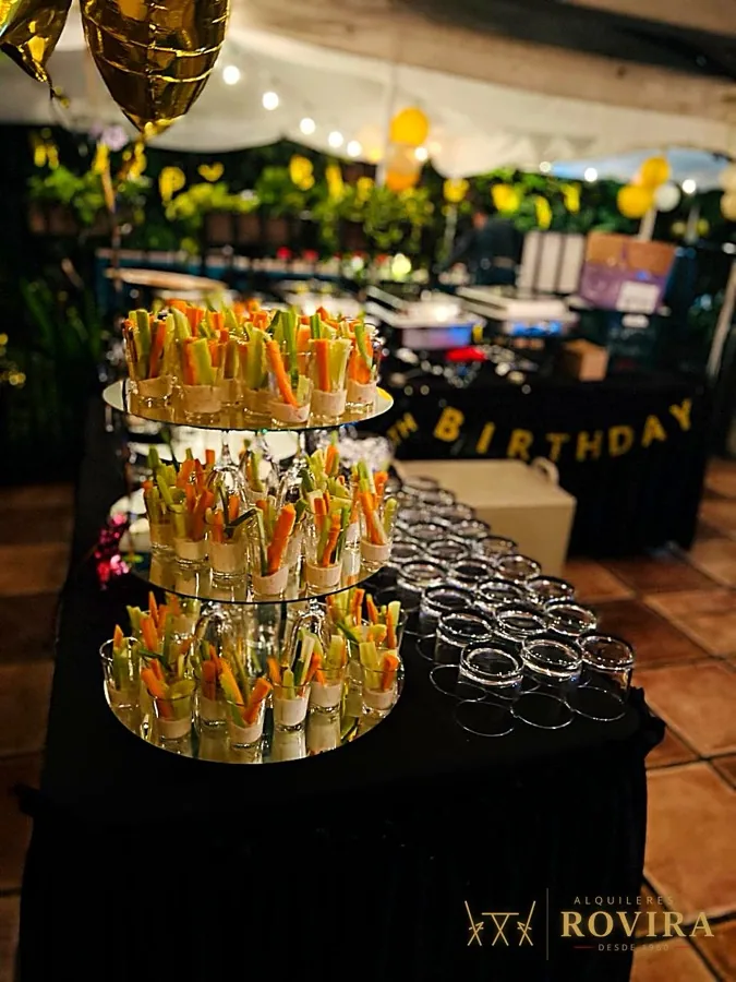 Buffet de cumpleaños con postres en niveles, mesa negra y dorada
