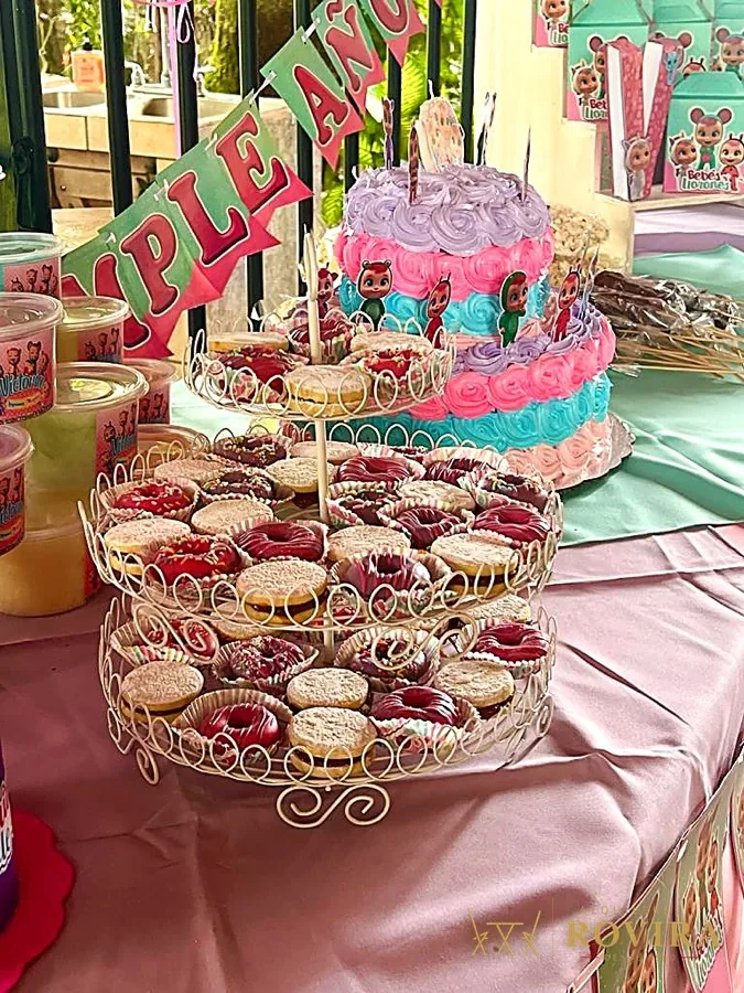 Pastel y cupcakes en exhibidor, mesa de dulces rosa y turquesa