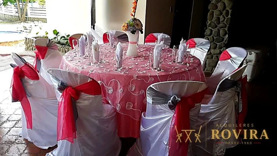 Mesa redonda con overlay de encaje rosa y sillas con lazo rosado