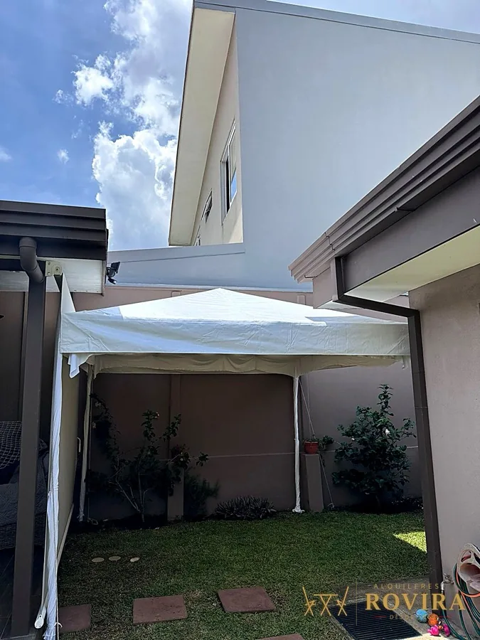 Toldo blanco tipo cochera en el exterior de una casa