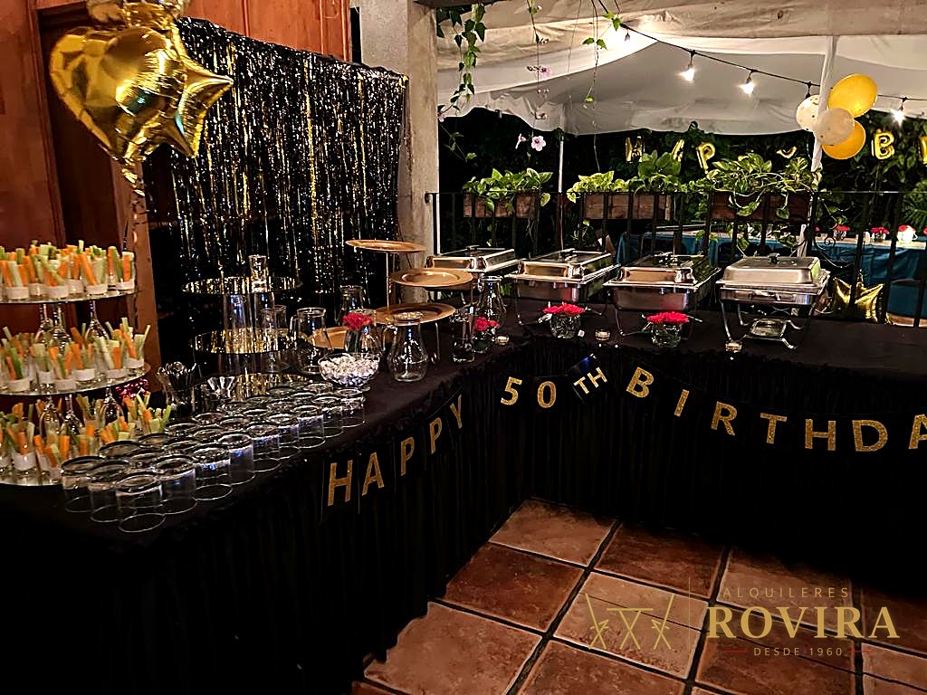 Buffet temático elaborado para una celebración de cumpleaños 50, con globos y ambientación dorada y negra